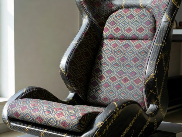 Natural-light photograph of a carbon-Kevlar bucket seat trimmed with woven Kyoto geometric brocade center cushions